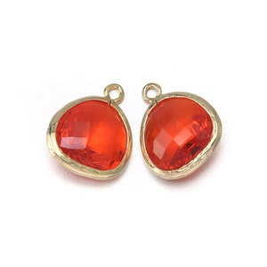May include: Two gold-toned pendant charms with a red faceted glass stone. The stones are shaped like a teardrop with a rounded top and a pointed bottom.