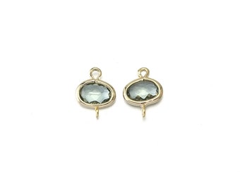 May include: Two gold-toned oval-shaped charms with a clear, faceted, light green gemstone. Each charm has a loop at the top and a small loop at the bottom.