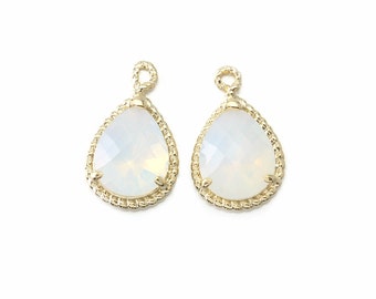 May include: Two gold-tone teardrop-shaped pendants with white opal stones. The pendants have a rope-like design around the edges.