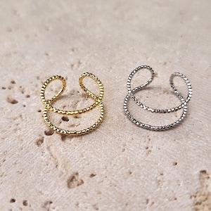 May include: Two ear cuffs, one gold and one silver, with a triple-ring design. Each ring is made of small beads.