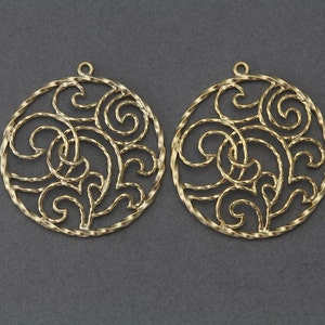 May include: Two gold-toned metal earrings with a circular filigree design. The design features a swirling pattern of leaves and vines.