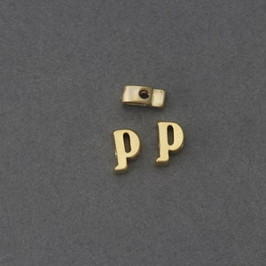 May include: Two gold-colored letter P charms with a hole for threading on a necklace or bracelet.