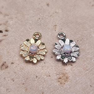May include: Two gold and silver flower charms with an iridescent opal center. The charms are perfect for jewelry making or adding a touch of whimsy to any project.