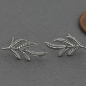 May include: A pair of silver earrings shaped like olive branches. The earrings are small and delicate, and they would make a great gift for someone who loves nature.