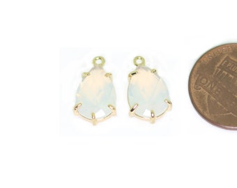 May include: Two gold-tone teardrop-shaped pendants with clear opal stones. The pendants are about the size of a US penny.