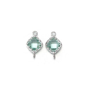 Può includere: Due ciondoli in argento con una pietra preziosa quadrata verde chiaro incastonata in una cornice d'argento. Ogni ciondolo ha un piccolo anello nella parte inferiore.
