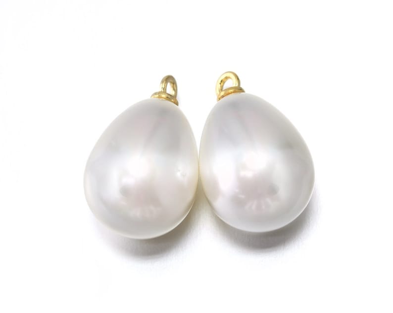 May include: Two white pearlescent teardrop-shaped pendants with gold jump rings.