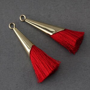 May include: Two red tassel earrings with gold metal caps. The tassels are made of soft, silky threads.