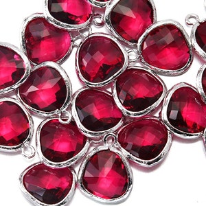 May include: A collection of pink faceted glass beads with silver-toned metal accents. The beads are shaped like teardrops and have a smooth, polished finish.