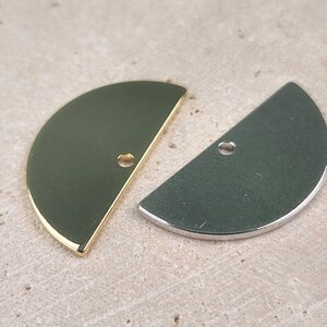 May include: Two half-circle metal charms, one gold and one silver, with a hole in the center.