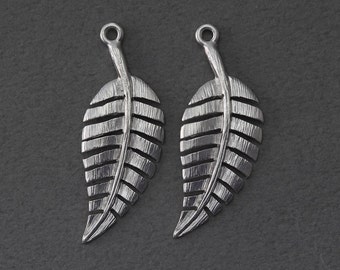 May include: Two silver leaf-shaped charms with a textured surface and a hole at the top for attaching to jewelry.