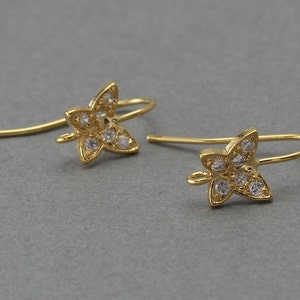May include: A pair of gold butterfly earring hooks with clear crystal accents.