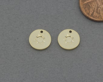 May include: Two gold-colored metal charms with a sun design. Each charm has a small hole at the top for attaching to a necklace or bracelet.