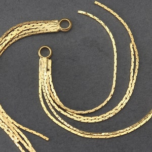 May include: Two gold chain tassel earrings with multiple strands of chain. The chains are connected at the top with a small gold loop.