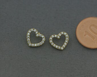 May include: A pair of gold heart-shaped earrings with clear cubic zirconia stones.