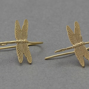 Op de afbeelding: Een paar gouden libellen oorbellen. Elke oorbel heeft een gedetailleerd libellenontwerp met delicate vleugels.
