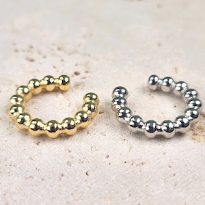 May include: Two ear cuffs, one gold and one silver, made of small round beads.