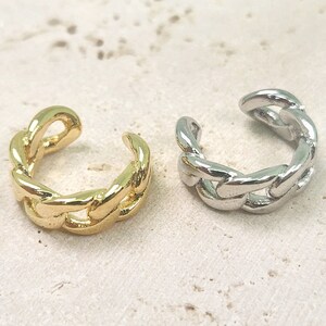 May include: Two gold and silver chain ear cuffs. The ear cuffs are made of a thick, chunky chain link design.
