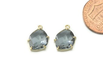 May include: Two gray faceted gemstone pendants with gold settings. The gemstones are teardrop shaped and have a faceted design.
