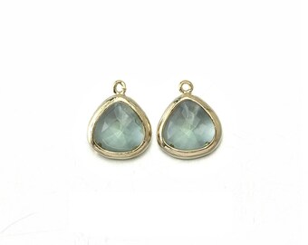 May include: Two gold-tone pendant charms with a light blue faceted glass teardrop shape.