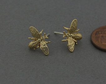 May include: A pair of gold bee stud earrings. The bees are detailed and have textured wings.