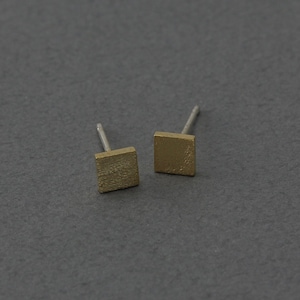 May include: A pair of gold square stud earrings with a textured finish.