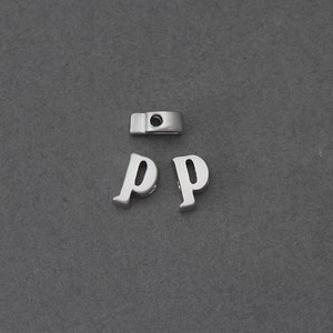 May include: Two silver letter charms in the shape of the letter "P". The charms are on a gray background.