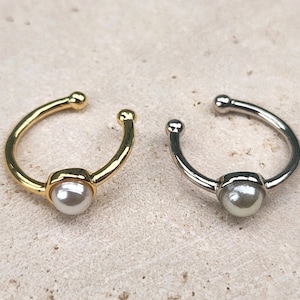 May include: Two ear cuffs with a pearl accent. One ear cuff is gold and the other is silver.