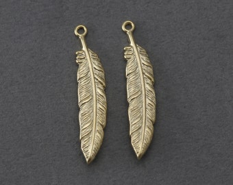May include: Two gold-toned metal feather charms with a loop at the top for attaching to jewelry or other crafts.