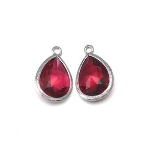 May include: Two silver teardrop-shaped pendants with red crystal accents.