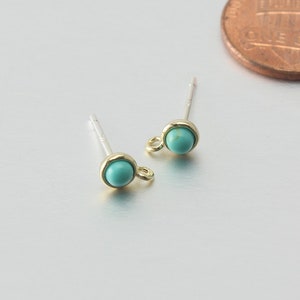 May include: A pair of silver stud earrings with a turquoise stone and a gold loop on each earring.