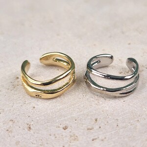 May include: Two ear cuffs, one gold and one silver, with a double-line design.