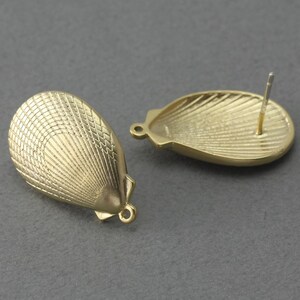 May include: A pair of gold-tone metal earring findings in the shape of a seashell. The findings have a post on the back for attaching to an earring.