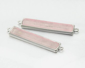 Peut inclure: Deux pendentifs en forme de barre argentés avec un insert en pierre rose clair. Les pendentifs ont une boucle à chaque extrémité pour être attachés à une chaîne ou un cordon.