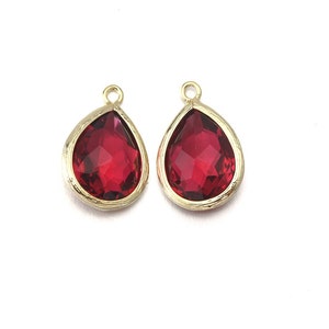 May include: Two red teardrop-shaped glass pendants with gold settings.