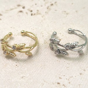 May include: Two delicate leaf and vine rings, one gold and one silver, with small clear stones set in the leaves.