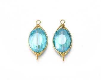 Op de afbeelding: Twee met goud omwikkelde ovale turquoise blauwe glazen kralen met een gouden lus aan de boven- en onderkant.