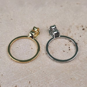 May include: Two simple circle pendant earrings, one gold and one silver. The earrings have a simple, minimalist design.
