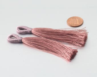 May include: Two pink tassel trim with a loop at the top. The tassels are made of soft, fine threads.