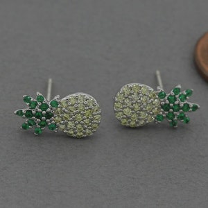 Op de afbeelding: Een paar zilveren ananas oorbellen met groene en gele zirkonia stenen.