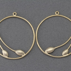 May include: A pair of gold-toned metal hoop earrings with a delicate floral design. The earrings are circular and have a thin wire design that creates a floral pattern.