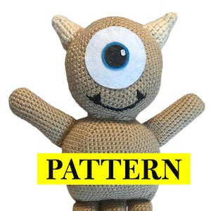 May include: Crochet pattern for a one-eyed monster amigurumi toy. The toy is brown with a white eye and a black mouth. The pattern is labeled "PATTERN" in yellow.