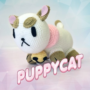 May include: A white crocheted plush toy with brown and pink accents. The toy is shaped like a cat with large eyes and a pink nose. The toy is holding a small yellow crocheted ball. The text "PUPPYCAT" is written in pink letters on a white background.
