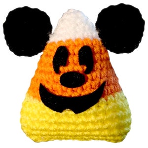 May include: Crocheted candy corn with a Mickey Mouse face. The candy corn is yellow, orange, and white. The Mickey Mouse face is black.