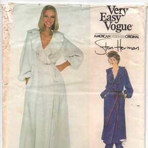 May include: A sewing pattern for a long, white robe with a ruffled collar and a sash. The pattern is by Stan Herman and is part of the Very Easy Vogue line. The pattern number is 2039.