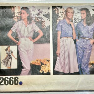 May include: A sewing pattern envelope labeled 2666 featuring illustrations of clothing options. One shows a striped shirt with light-colored trousers. Another shows a floral blouse with a striped skirt or matching floral trousers with a belt.