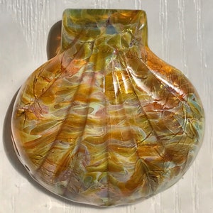 May include: A glass seashell ornament with a swirling pattern of gold, brown, and white.