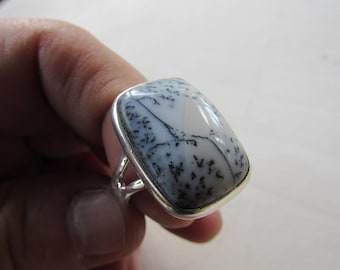 May include: A silver ring with a large, rectangular, white and gray agate stone. The stone has a dendritic pattern of black lines.