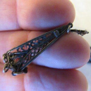 Op de afbeelding: Een zilveren filigraan hanger met een rode steen. De hanger is bevestigd aan een ketting met een zilveren sluiting.