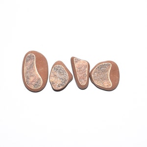May include: Four smooth, brown stones with white and light brown patterns. The stones are arranged in a row.